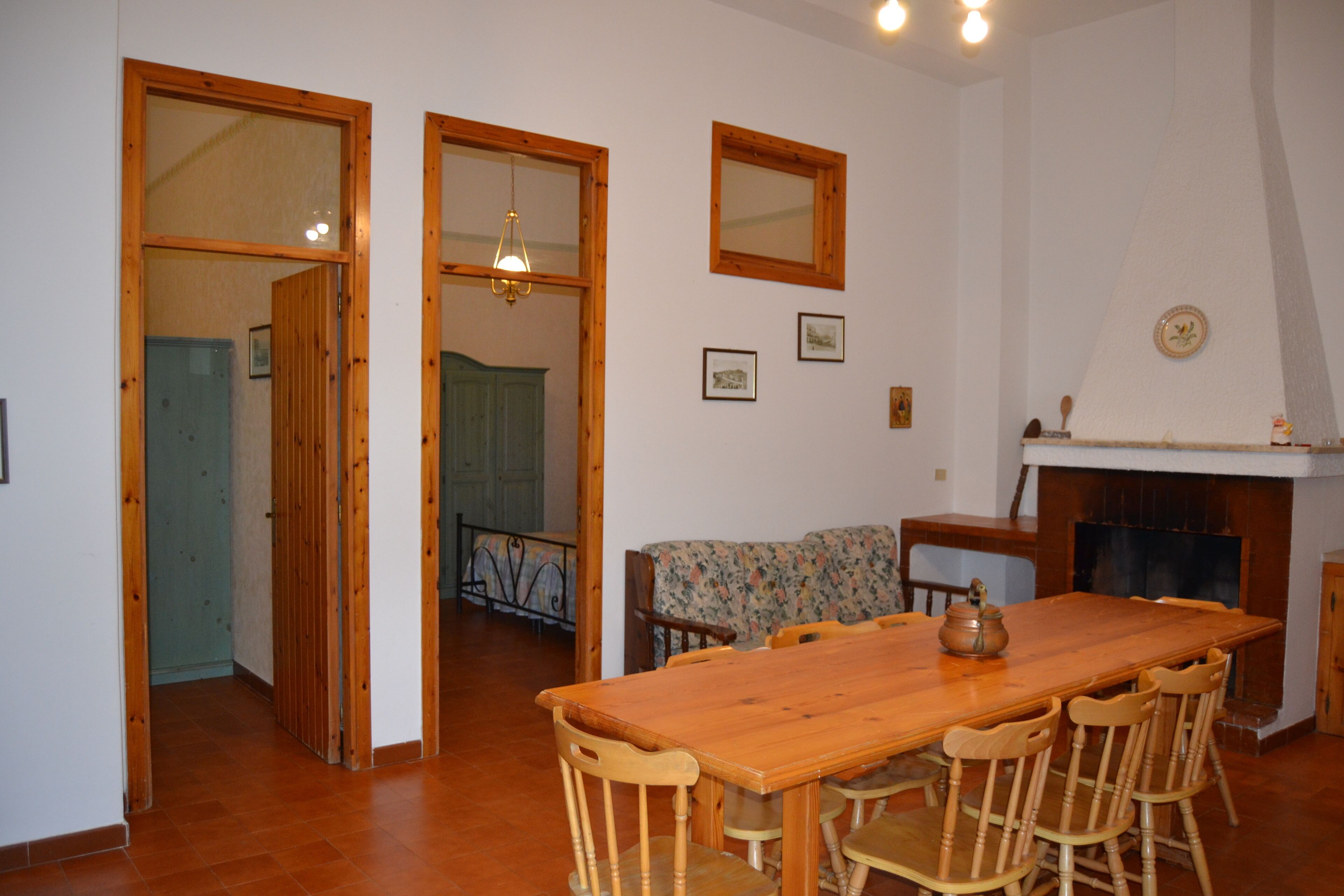 Zona pranzo con tavolo e sedie in legno, un divano e un camino.