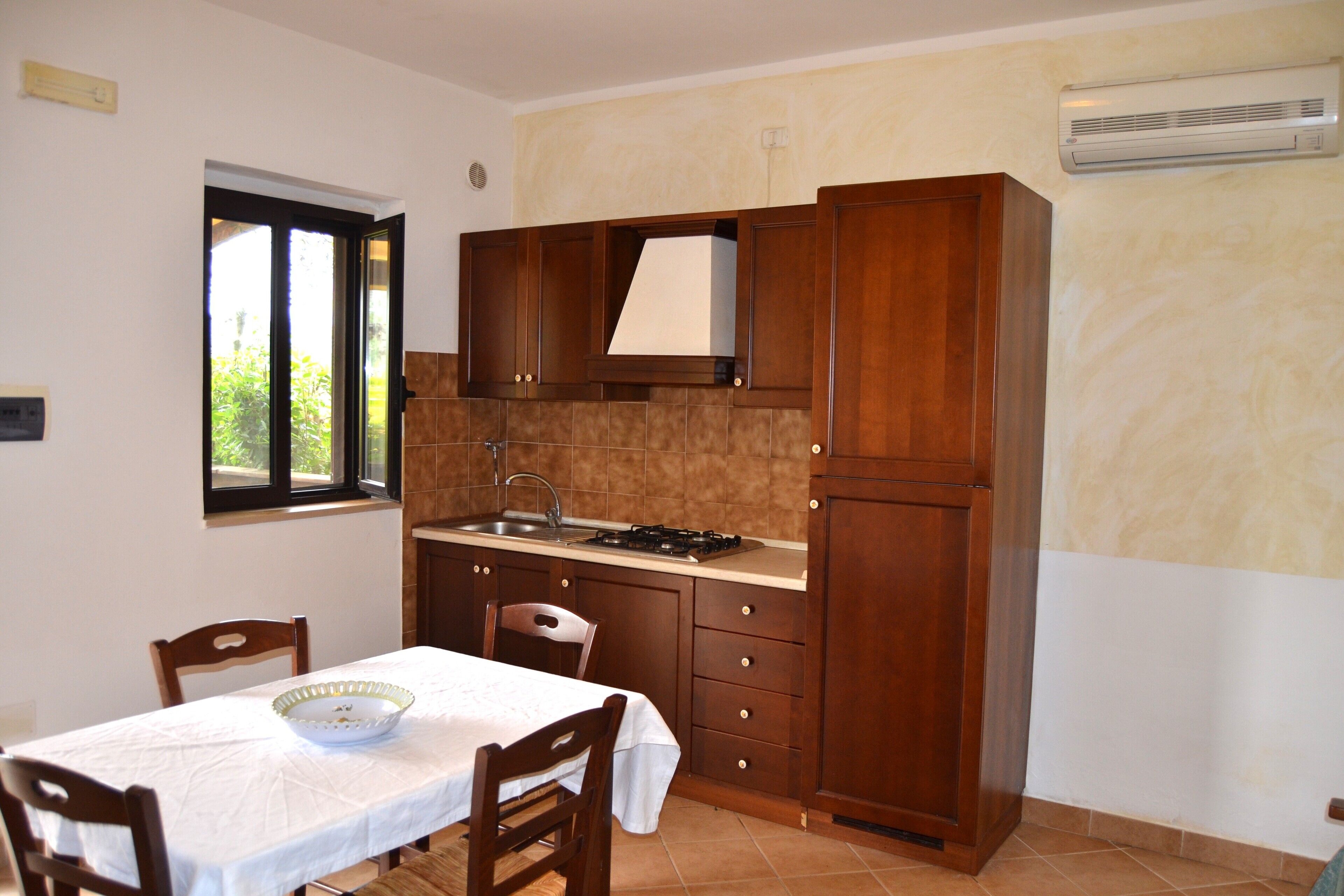 A kitchen with wooden cabinets, a gas stove, a sink, and a window.
