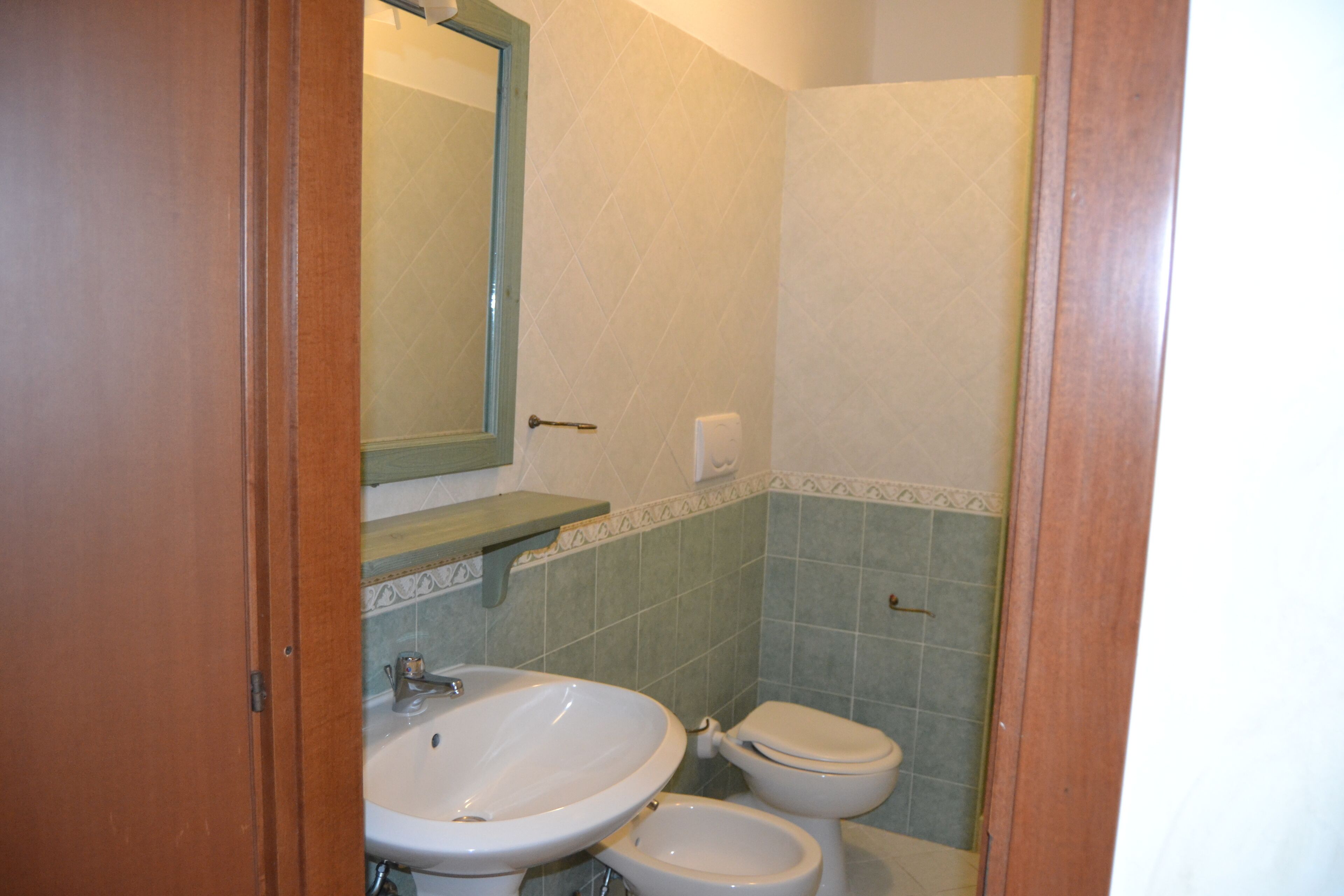 Un baño con lavamanos, inodoro y espejo.