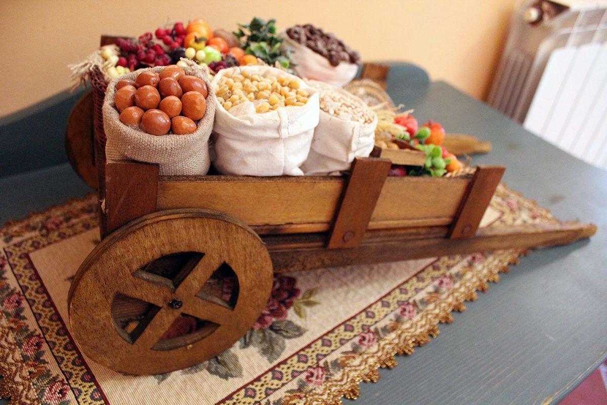 Um carrinho de madeira com diversos alimentos e uma roda grande.
