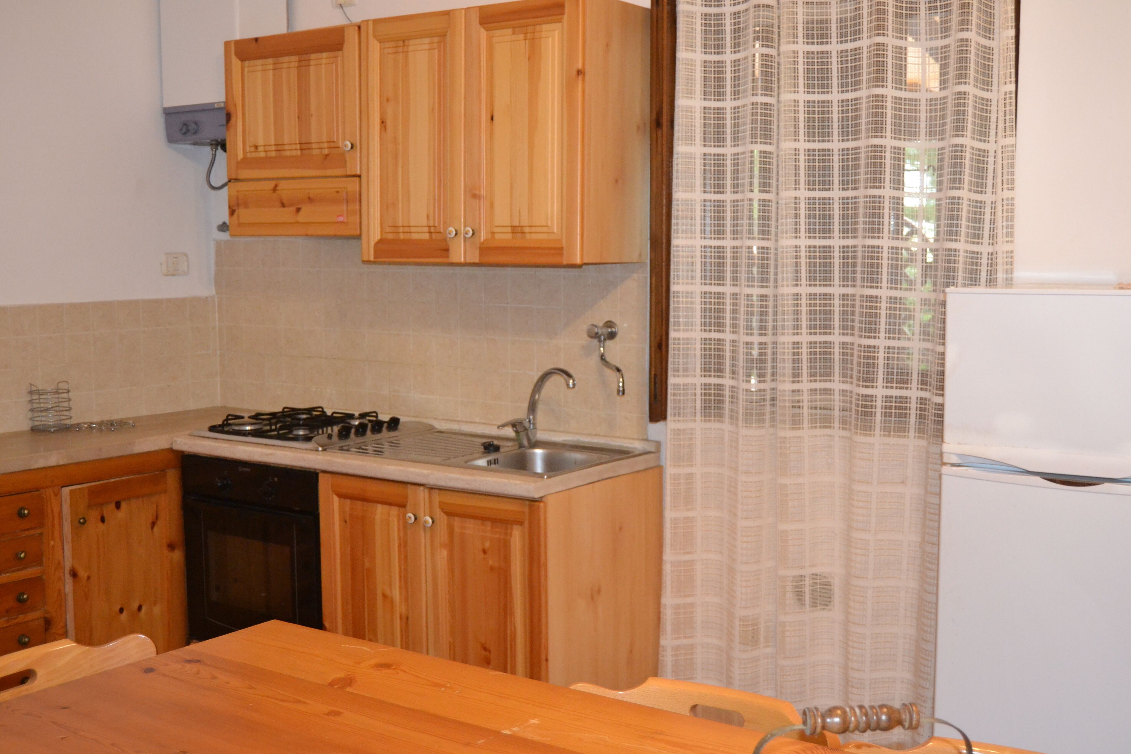 Una cocina con armarios de madera, un fregadero, una estufa y un refrigerador.