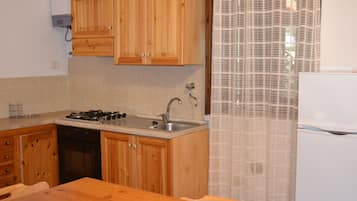 Una cocina con armarios de madera, un fregadero, una estufa y un refrigerador.