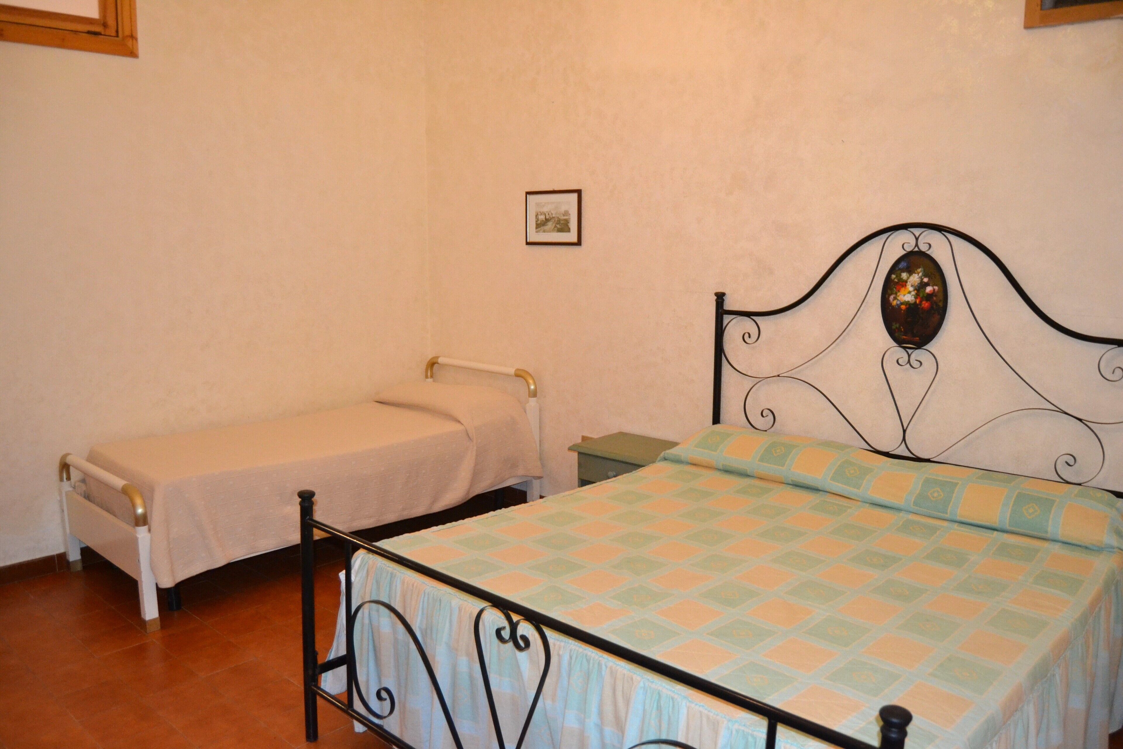 A bedroom with two single beds, one with a plain bedspread and the other with a patterned bedspread.
