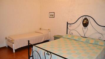 A bedroom with two single beds, one with a plain bedspread and the other with a patterned bedspread.