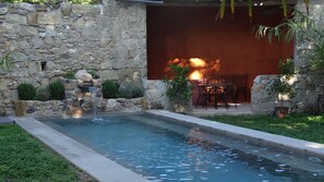 A stone wall with a small waterfall feature and a pool.