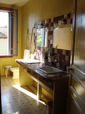A kitchen with a tiled backsplash, two sinks, a window with an open door, and a toilet. - House of CHARACTER with SWIMMING POOL in an AUTHENTIC VILLAGE, NEAR the SEA (Capestang)