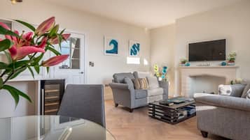 A modern living room with a fireplace, two grey sofas, a coffee table, and a flat-screen TV.