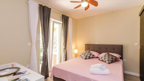 A bedroom with a bed, a ceiling fan, and a window with curtains. - 1 bedroom cozy home in Gruda (Gruda)