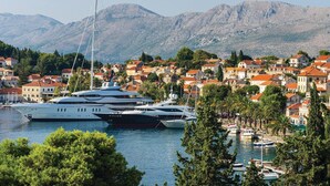 A marina with several yachts docked, surrounded by a coastal town with red-roofed buildings and mountains in the background. - 1 bedroom cozy home in Gruda (Gruda)