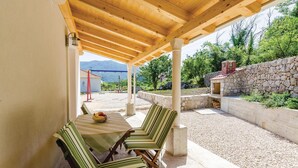 An outdoor patio with a table and chairs, a stone wall, and a stone oven. - 1 bedroom cozy home in Gruda (Gruda)