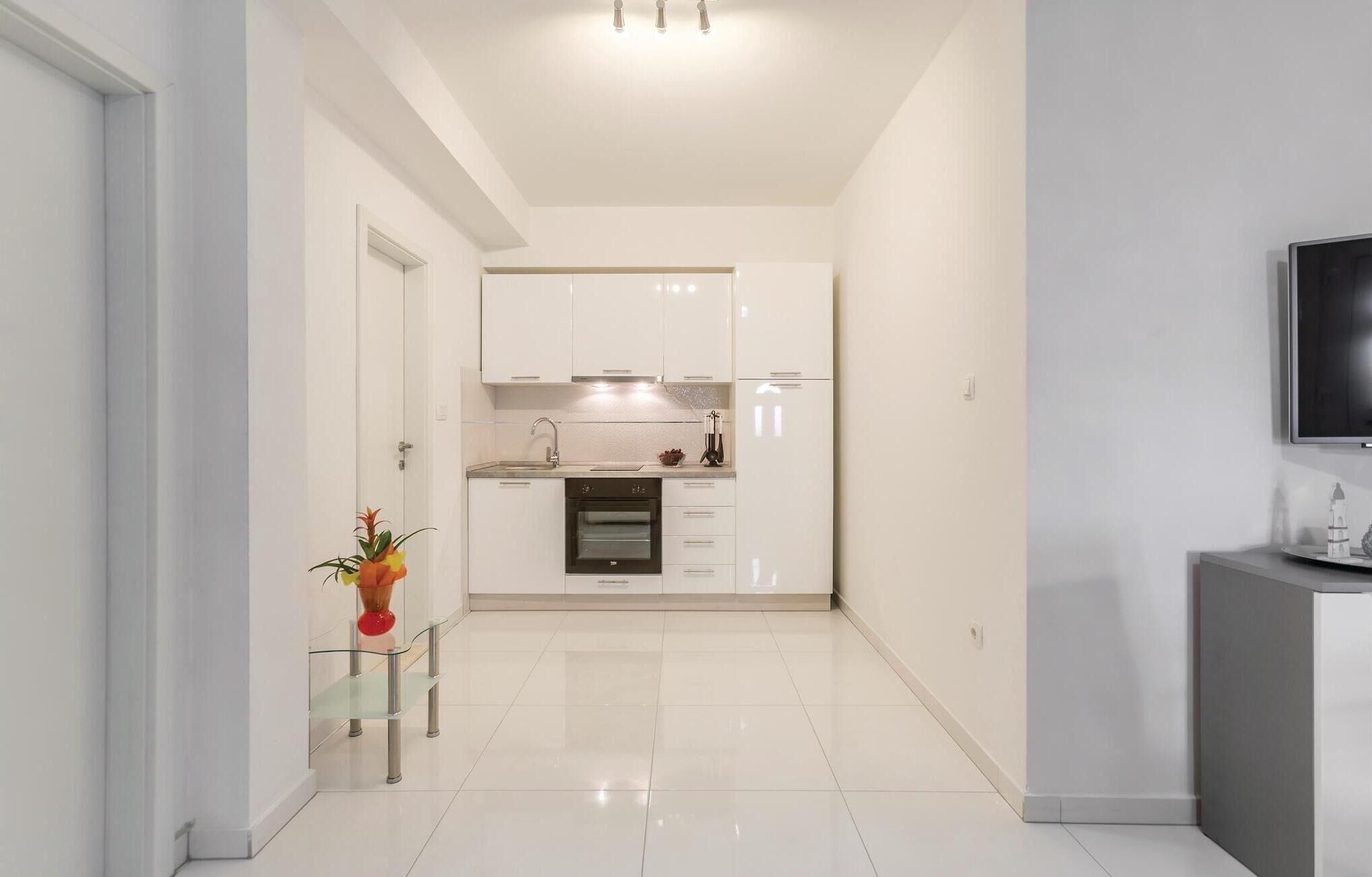 A modern kitchen with white cabinets, a built-in oven, and a small countertop.