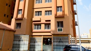 Un edificio de varios pisos con un diseño arquitectónico moderno, que presenta una serie de balcones y grandes ventanales.