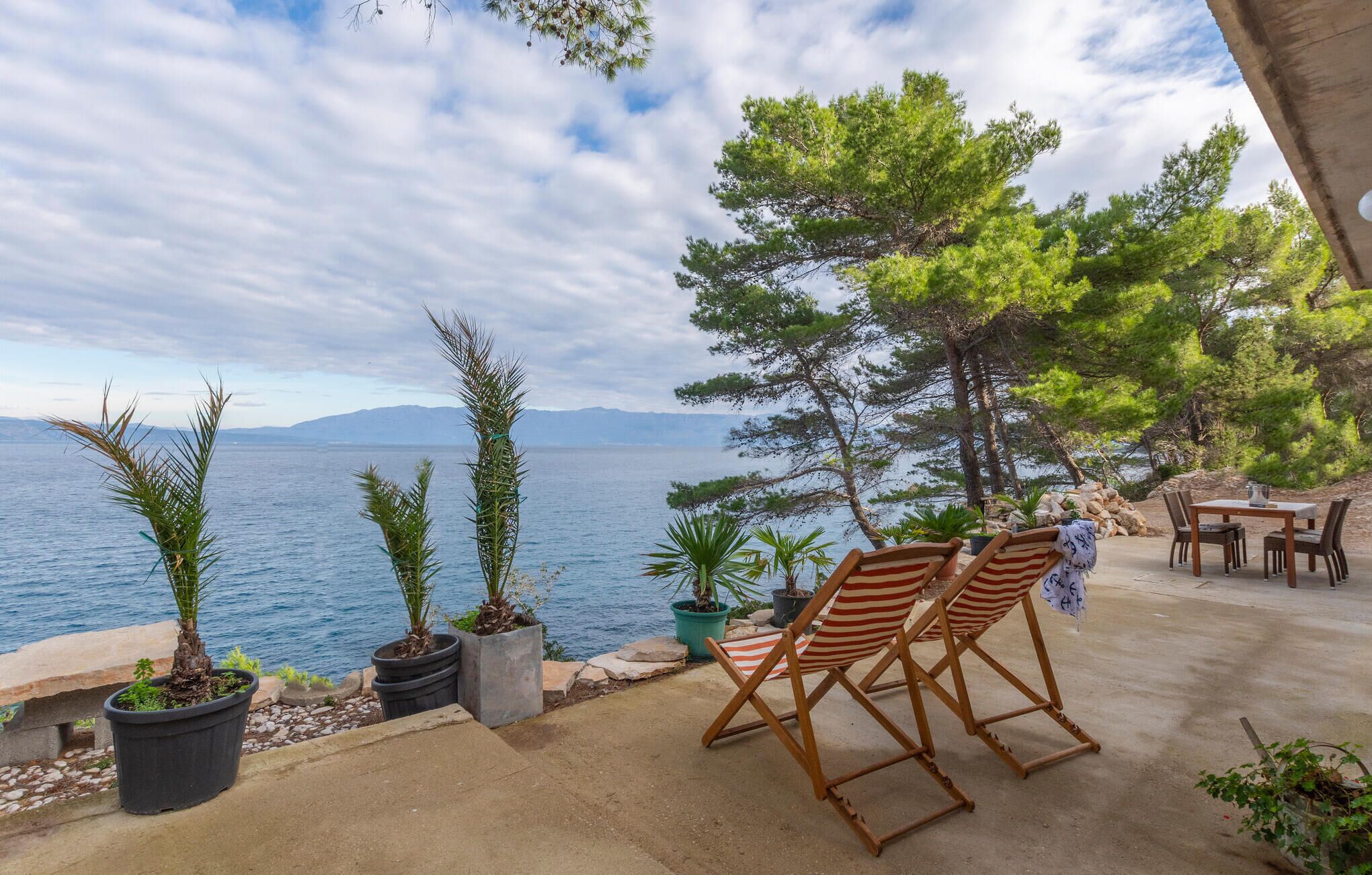 Une terrasse avec deux chaises longues à rayures, une table et des plantes en pot.