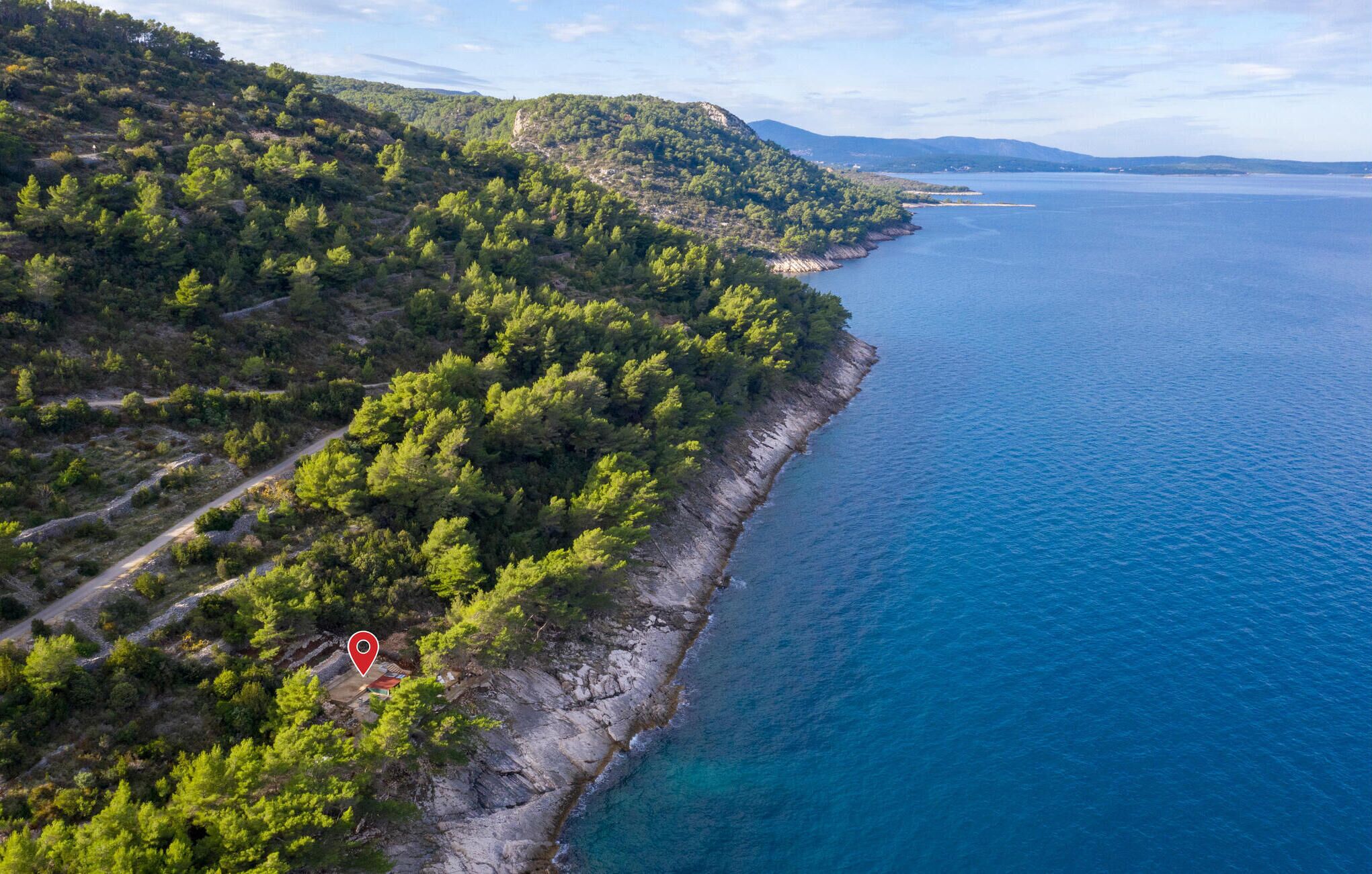 Eine Vogelperspektive einer Küstenlandschaft mit dichtem Grün und blauem Meer.