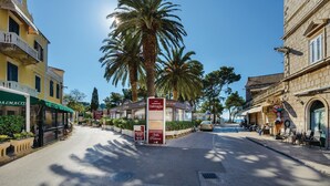 Una calle con el cartel de un hotel boutique, palmeras y edificios con locales comerciales.