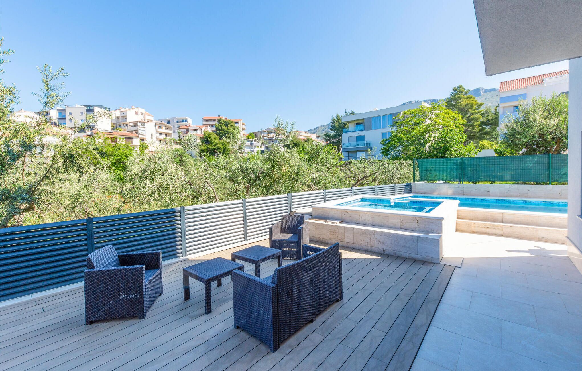 A rooftop terrace with a pool, outdoor furniture, and a view of surrounding buildings.