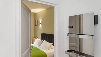A hotel room with a bed, a bedside table, a wall-mounted TV, and a door.