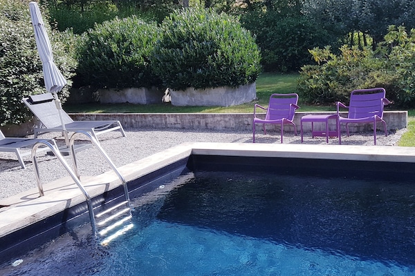 Una piscina al aire libre, sombrillas, sillones reclinables de piscina