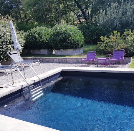 Una piscina al aire libre, sombrillas, sillones reclinables de piscina