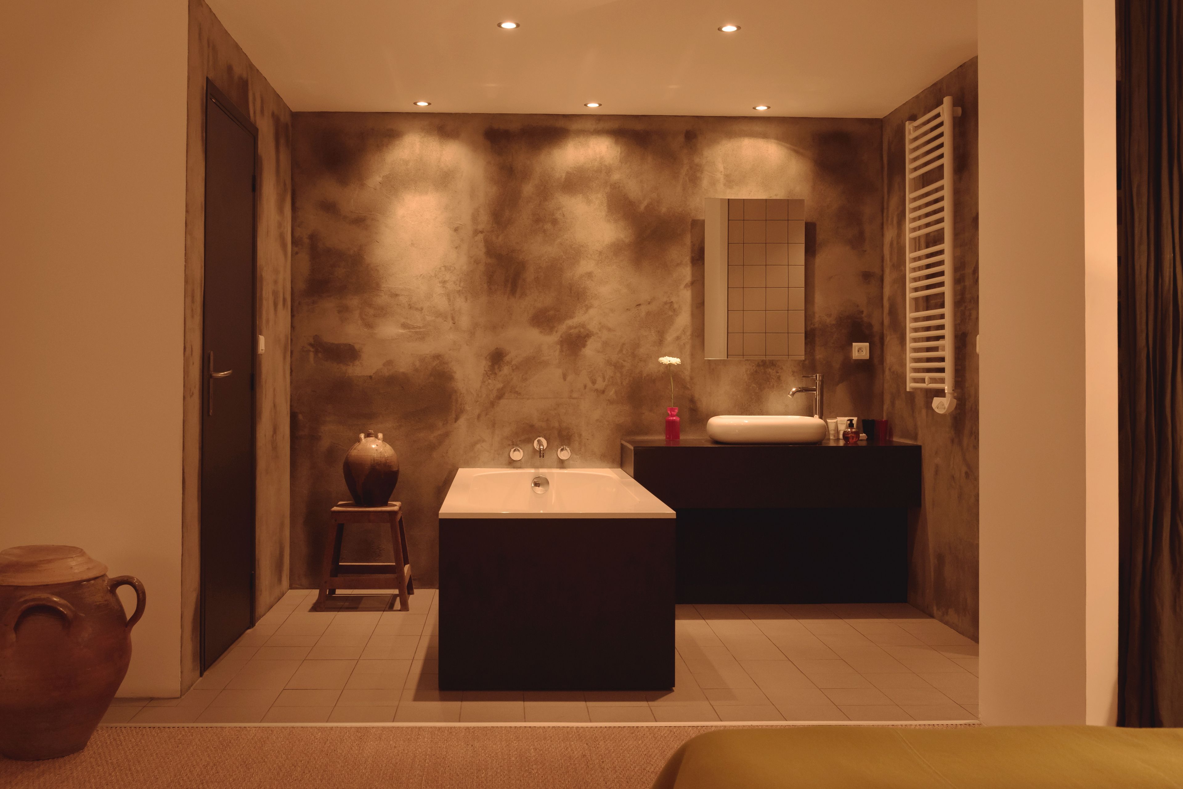 A modern bathroom with a large bathtub, a vanity with a mirror, and a towel rack.