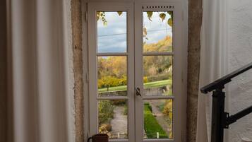 Uma porta branca com vista para um caminho no jardim e árvores.
