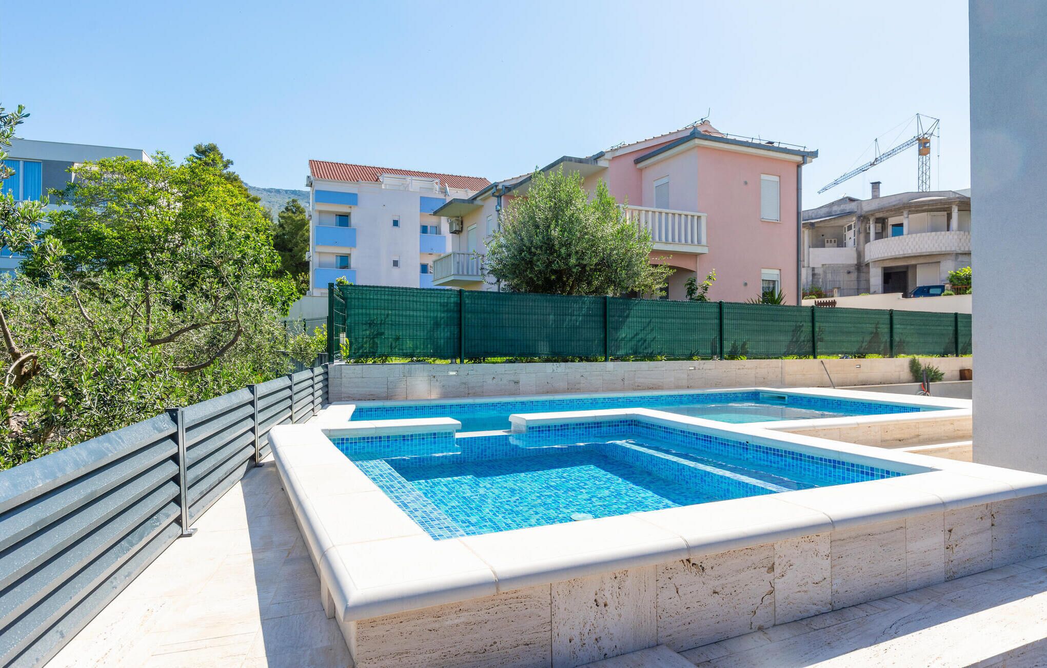 A rectangular swimming pool with a tiled edge, surrounded by a low stone wall.