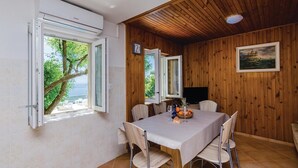 A dining area with a table, chairs, and a view of the sea through open windows. - Gorgeous home in Slano (Slano)