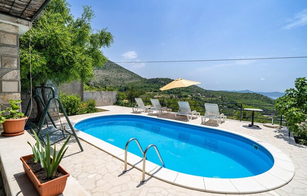 Relax by the pool surrounded by a patio, lounge chairs, and lush greenery, with a breathtaking mountain view.