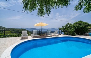 Relax by the serene pool surrounded by a tranquil landscape and distant hills.