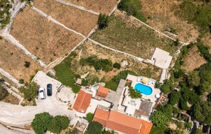 Residential property with a swimming pool, red-roofed building, and driveway.