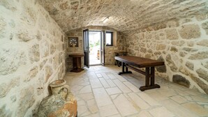 A stone-walled room with a wooden table and bench, a small sink, and a window. - Gorgeous home in Slano (Slano)