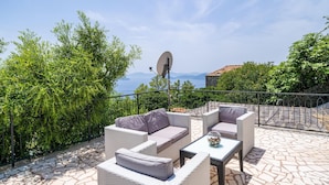 An outdoor seating area with wicker furniture and a satellite dish, overlooking a scenic landscape with trees and a view of the sea. - Gorgeous home in Slano (Slano)