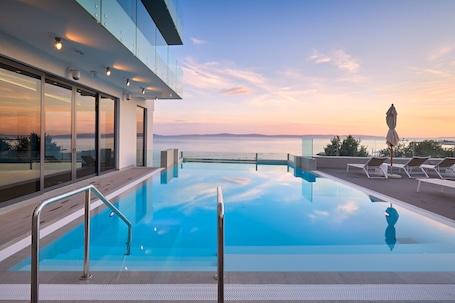 Una piscina techada, una piscina al aire libre, sombrillas