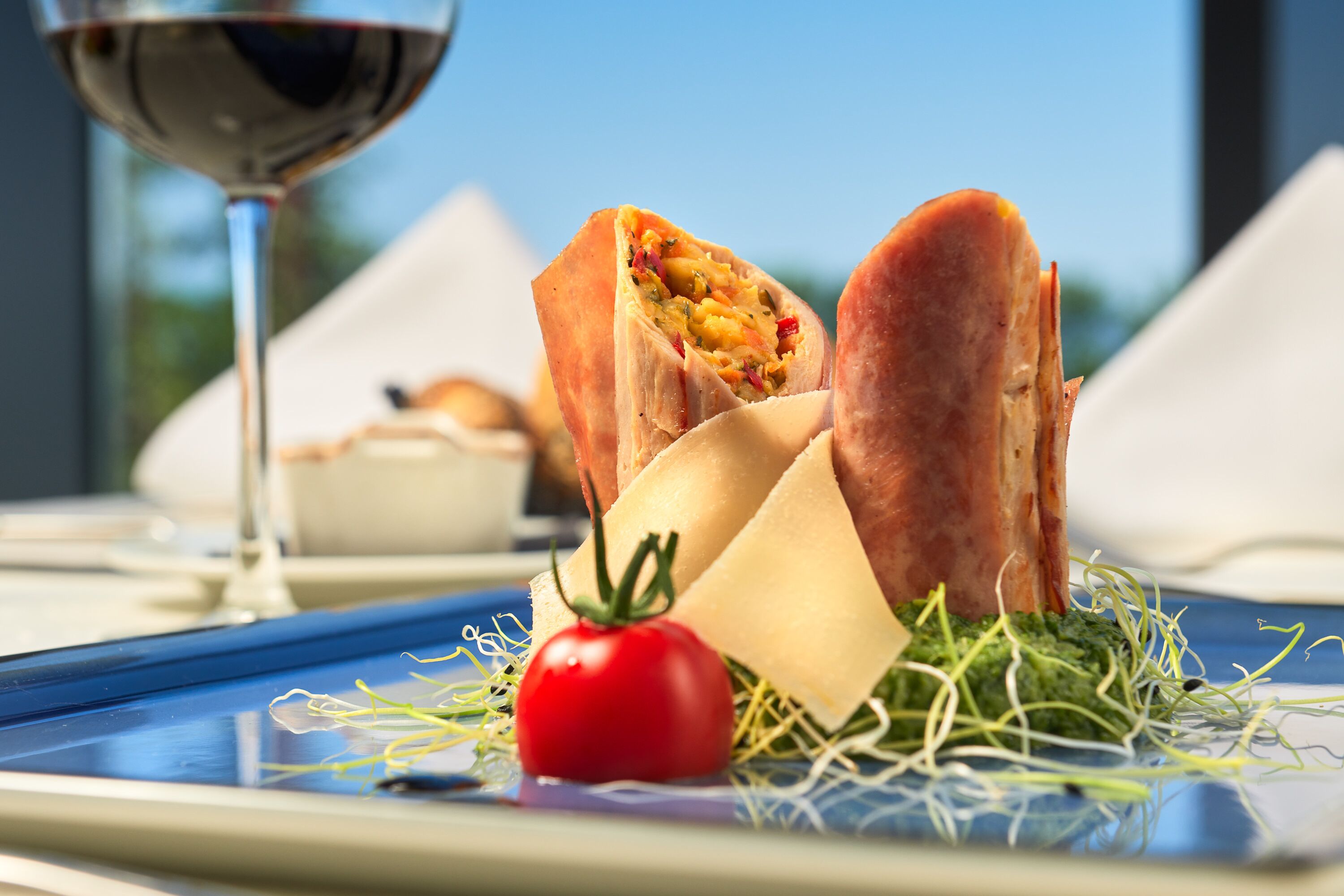 A meal with a sandwich, a tomato, and a piece of cheese on a plate.