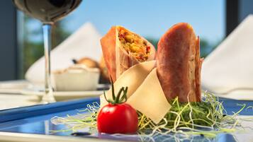 A meal with a sandwich, a tomato, and a piece of cheese on a plate.