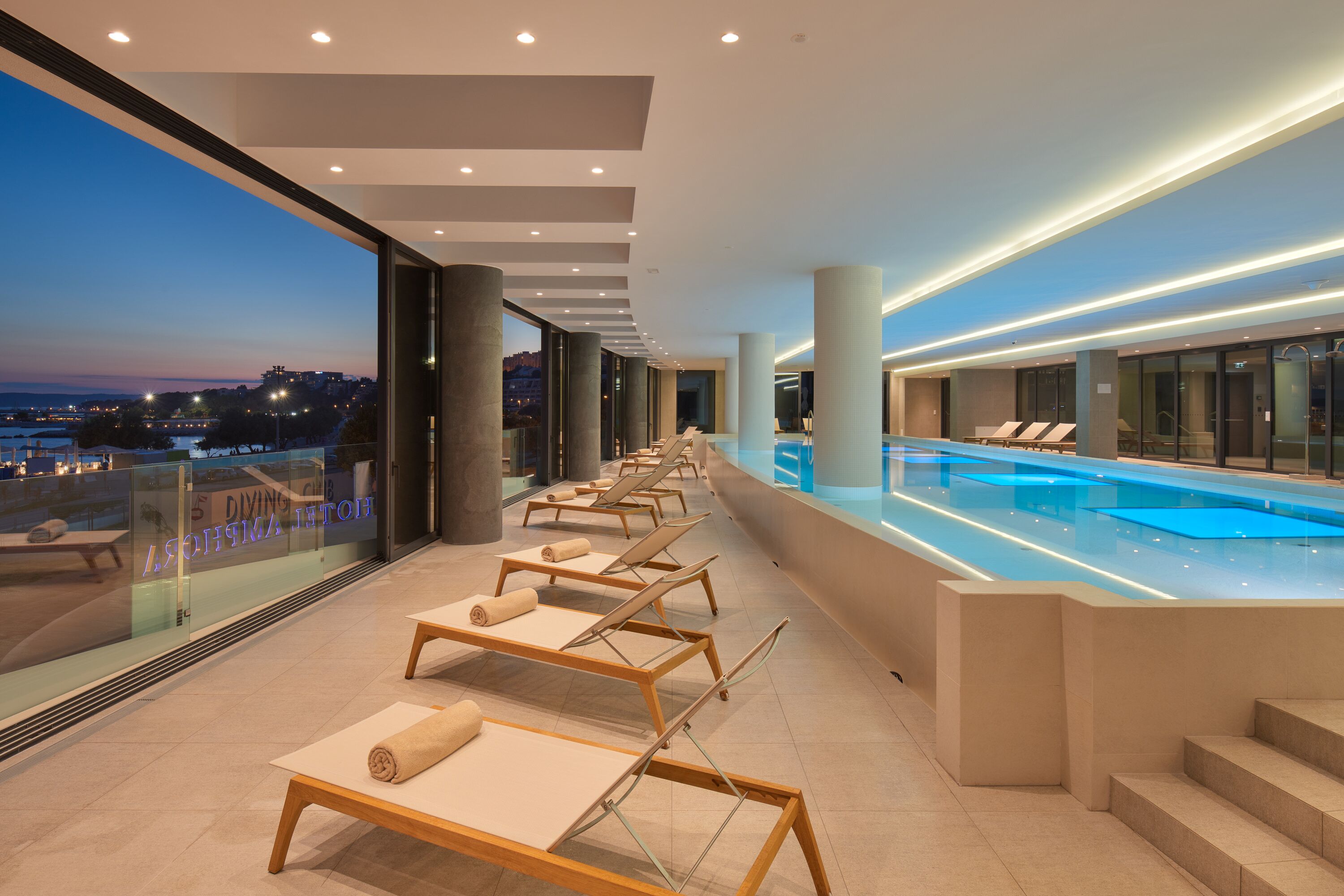 Una piscina techada, una piscina al aire libre, sombrillas