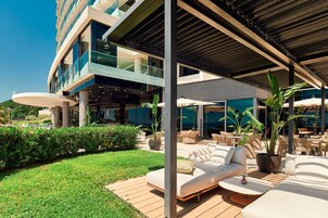 Un espacio lounge moderno al aire libre con terraza de madera, asientos exteriores y plantas en macetas.