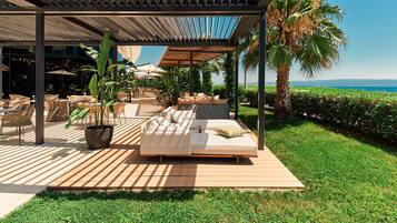 Un área de estar al aire libre cubierta con terraza de madera, un sofá y plantas en macetas.