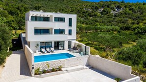 Una moderna casa a due piani con piscina, immersa nel verde e circondata da dolci colline.