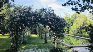 A garden with a pergola covered in flowers, a pathway, and a pond. - Authentic farmhouse with large swimming pool, near Aix en Provence (Pourcieux)