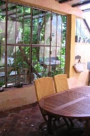 A room with a round table and chairs, large windows, and a hanging bag. - Authentic farmhouse with large swimming pool, near Aix en Provence (Pourcieux)