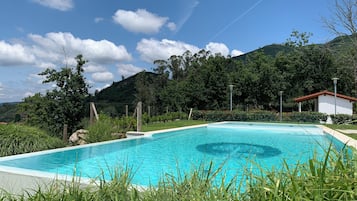 Una piscina al aire libre de temporada, sillones reclinables de piscina