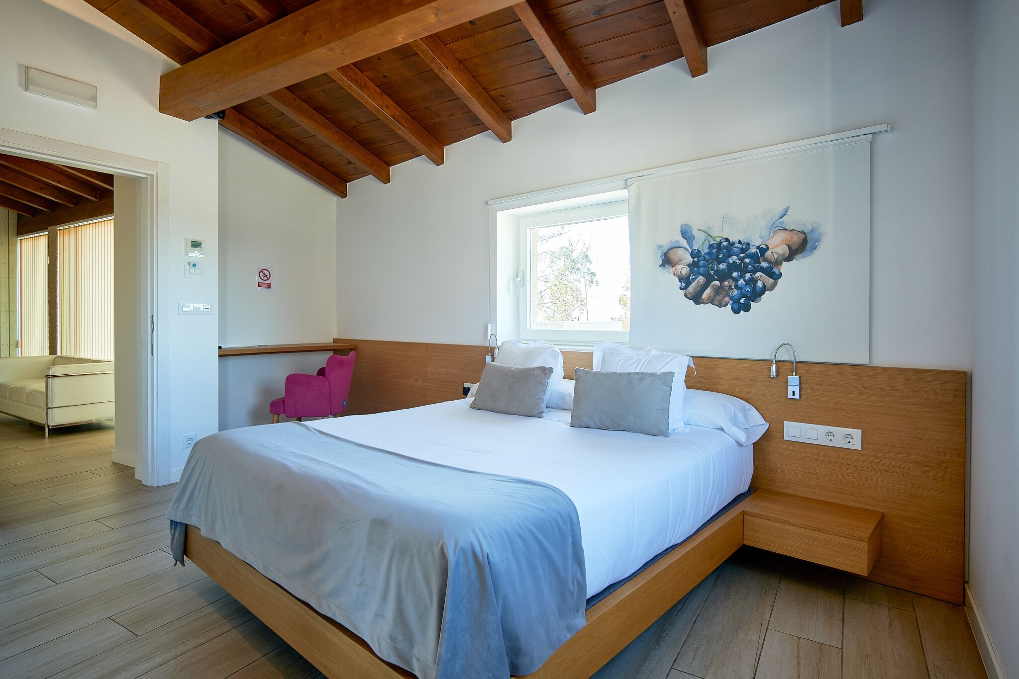 Ein modernes Schlafzimmer mit Holzboden, einem großen Bett mit Kopfteil, einem Nachttisch und einem Fenster.
