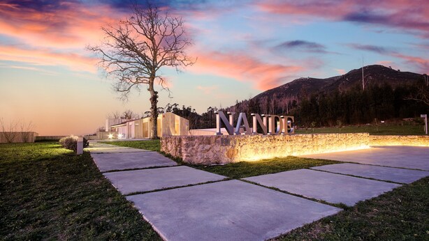A modern hotel entrance with a stone wall and illuminated letters spelling "NANTHE". - Hotel Nande (As Neves)