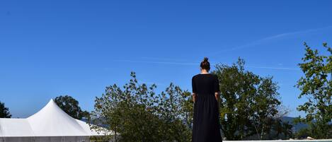 A person standing by a pool with a white tent and trees in the background.