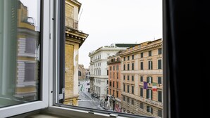 A view from a window of a street with historic buildings, including a building with the sign "ALBERGO QU". - Seven (Rome)