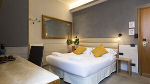 A modern hotel room with a large bed, bedside table, and a small bedside table. - Seven (Rome)