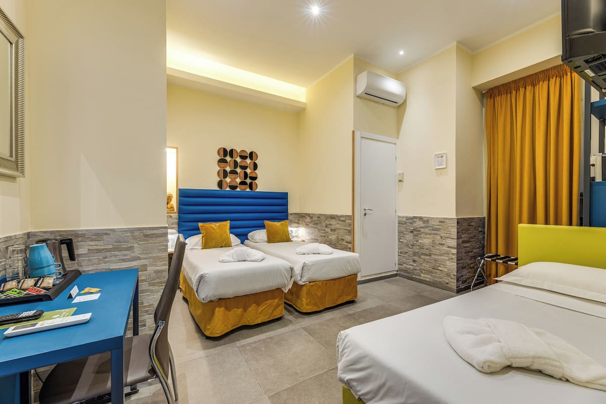 A hotel room with two beds, a desk, and a bathroom.
