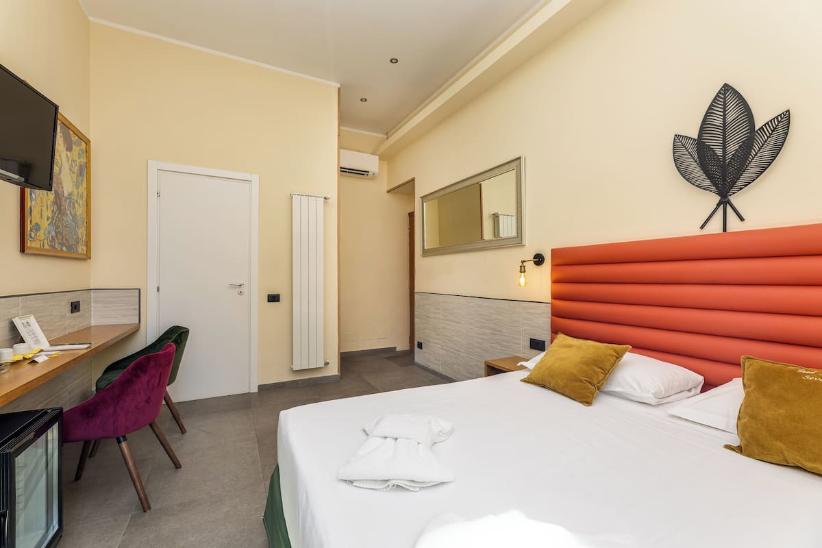 A hotel room with a bed, a desk, a chair, and a bathroom door.