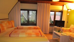 A hotel room with a bed, a television, a sofa, and a window with curtains. - Willischza (Burg (Spreewald))
